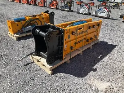 Equipo HMB1400 acoplado a excavadora, rompiendo material rocoso en terreno de difícil acceso.
